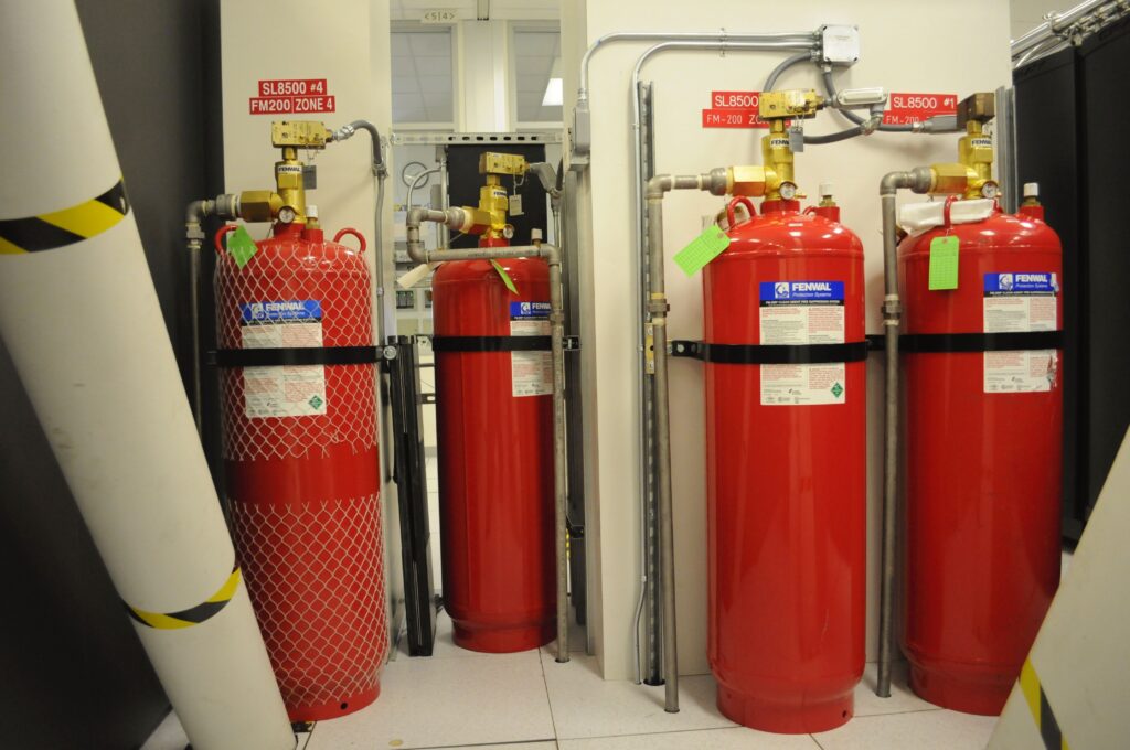 Clean agent fire suppression cylinders in a protected equipment room