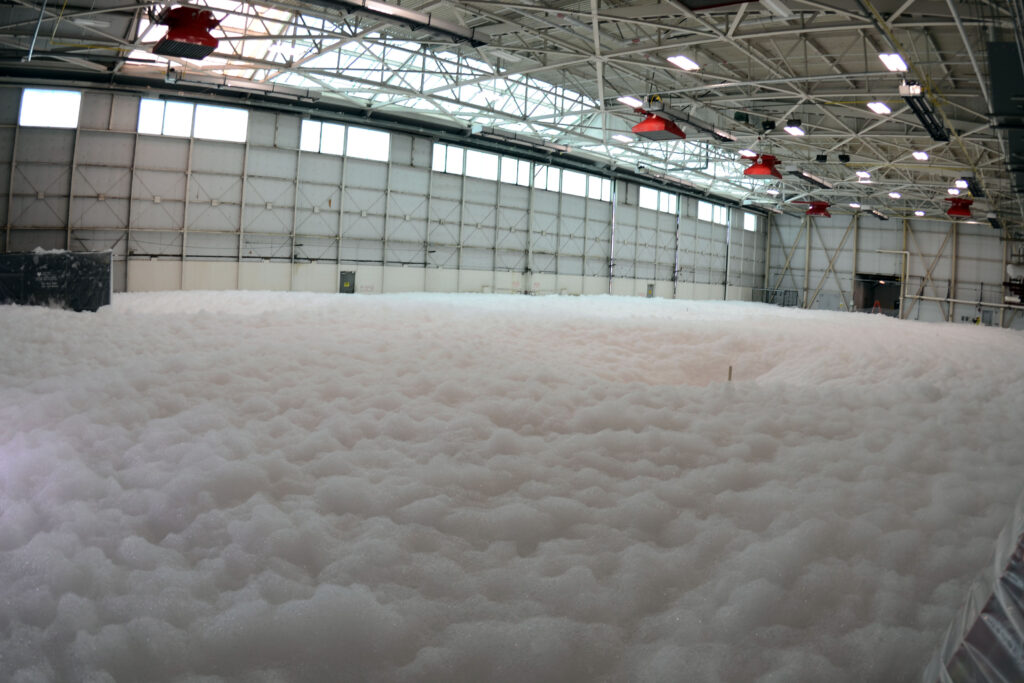 Aircraft hangar filled with high-expansion foam during a foam fire suppression system test